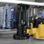 Bendi B55AC forklift lifting pallet off warehouse shelf.