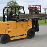 Drexel R60i5 fork truck transporting steel beams outdoors.