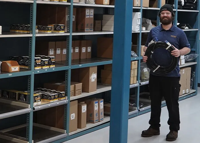Fairchild Equipment employee holding hose near parts inventory.
