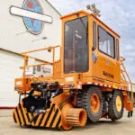 Rail King G7 mobile Railcar mover parked in front of building.