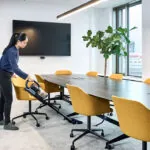 Advance VU200 upright vacuum cleaning floors under conference room table.