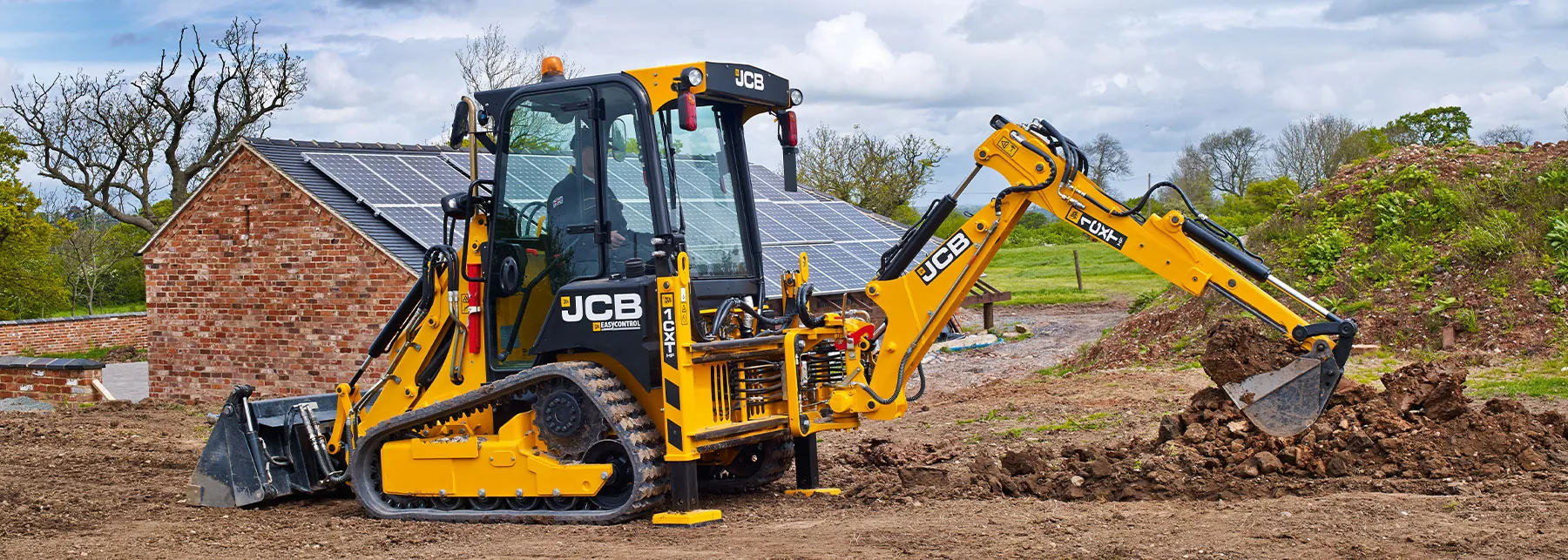 JCB 1CXT Backhoe Loader scooping dirt.