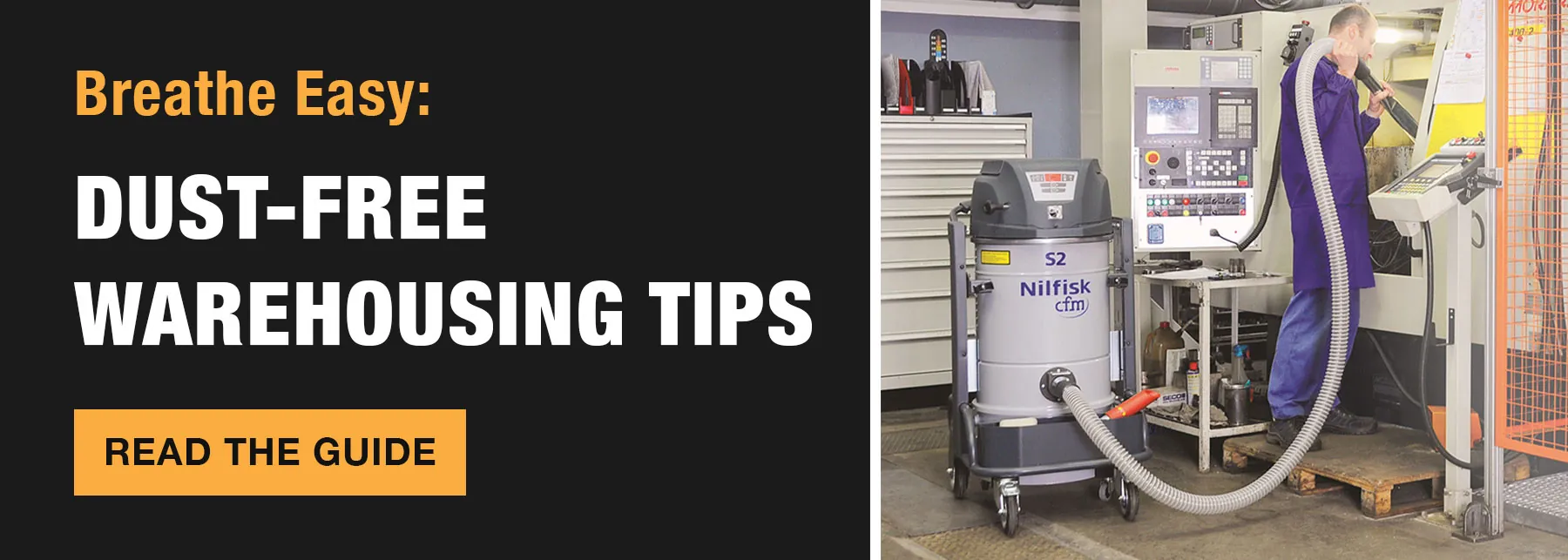 Worker cleaning machine with Nilfisk S2 vacuum. "Breathe Easy: Dust-Free Warehouse Tips. Read the Guide."