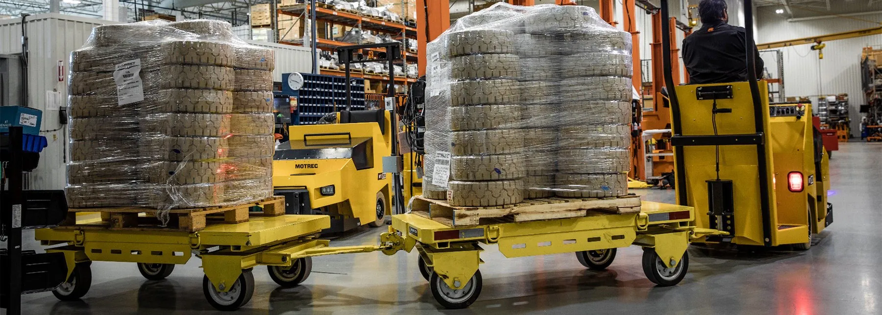 Motrec tow tractor towing trailers loaded with tires.
