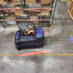 Advance CS7500 Sweeper Scrubber with safety lights cleaning warehouse floors.