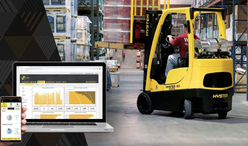 Hyster forklift in warehouse, with telematics tracking data visible on nearby computer and phone.
