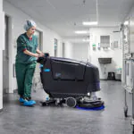 Nilfisk SC550 walk behind scrubber cleaning floors in a hospital's walkway.