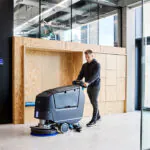 Nilfisk SC550 walk behind scrubber cleaning hallway floors.
