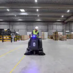 Nilfisk SW3000 rider sweeper cleaning floors in warehouse distribution facility.