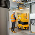 JCB S1932E compact scissor lift driving through tight doorway.