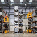 JCB S1932E compact scissor lifts raised in warehouse aisles.